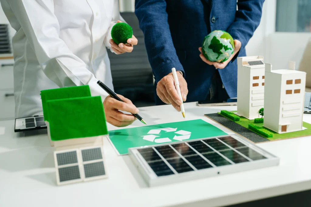 Manos sostienen esferas del planeta y revisan gráficos verdes sobre reciclaje durante auditoría energética en entorno sostenible.