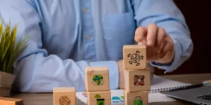 Una persona organiza cubos con símbolos de sostenibilidad y finanzas, reflejando los principios de transparencia y gestión responsable que promueven las NIS A1 y B1.