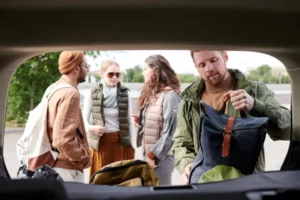 Vista desde dentro de un auto en donde se puede ver que ellos usan carpool, mientras acomodan las mochilas en la cajuela.