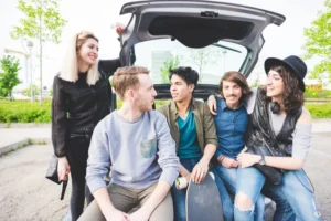 Vista general de un grupo de personas, algunas sentadas en la cajuela y otras de pie, haciendo uso correcto de carpool.